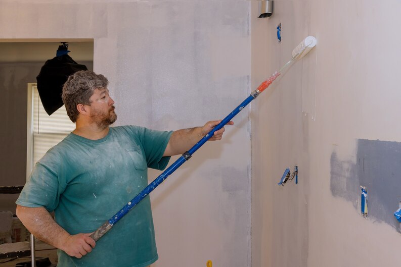A painter holding a brush, carefully applying vibrant colors to a canvas in a well-lit art studio in Dubai, with the iconic city skyline faintly visible through large windows.